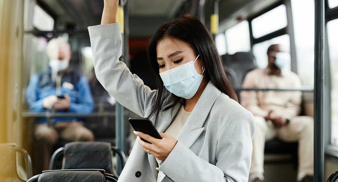 Woman wearing mask riding public bus.