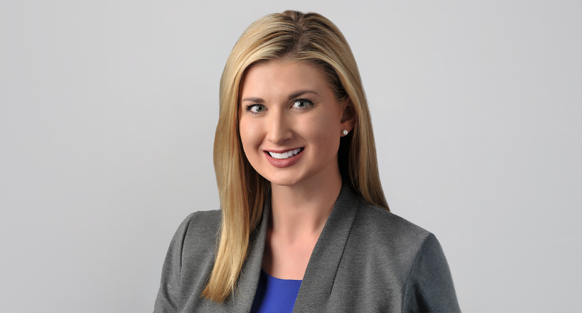 Headshot of female leader with blonde hair, gray suit jacket and blue short