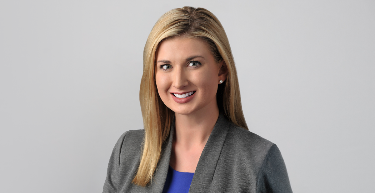 Headshot of female leader with blonde hair, gray suit jacket and blue short