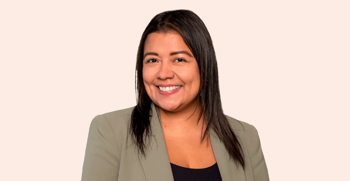 Women with black hair smiling in brown suit coat with black top