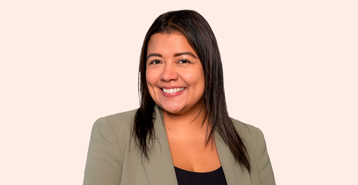 Women with black hair smiling in brown suit coat with black top